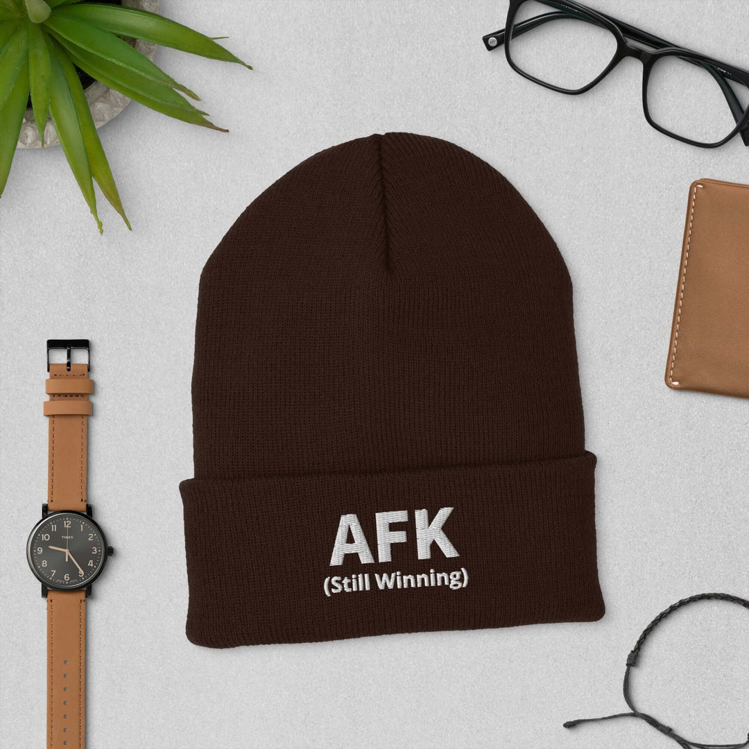 AFK Cuffed Beanie in brown with embroidered text, paired with accessories like glasses and a watch.